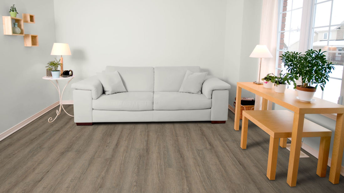 Apollo Traffic Vinyl Designboden Click 5,0 × 182 × 1220 mm – Beispielbild Wohnzimmer mit grauem Sofa